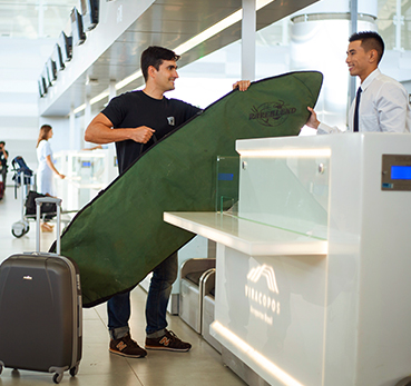 Passageiro fazendo check-in no aeroporo e despachando uma prancha de surf