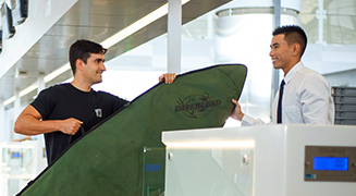 Passageiro fazendo check-in no aeroporo e despachando uma prancha de surf