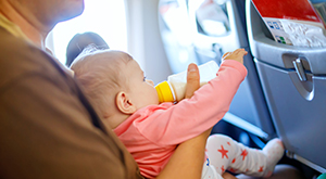 Pai dando mamadeira para bebê no avião