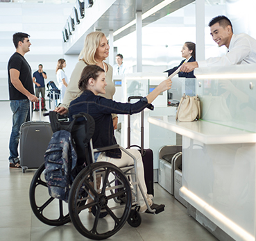 Passageira idosa acompanha passageira em cadeira de rodas na área de check-in de aeroporto