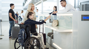 Passageira idosa acompanha passageira em cadeira de rodas na área de check-in de aeroporto