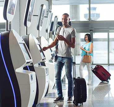 Homem fazendo check-in em totem de autoatendimento em aeroporto