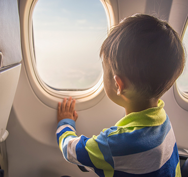 Criança sentada dentro de avião observando a janela