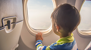 Criança sentada dentro de avião observando a janela